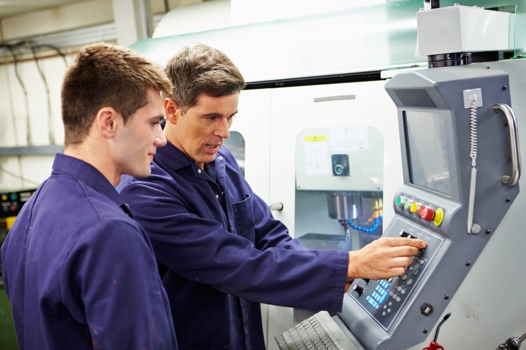 Two men adjusting the controls on an automated milling machine