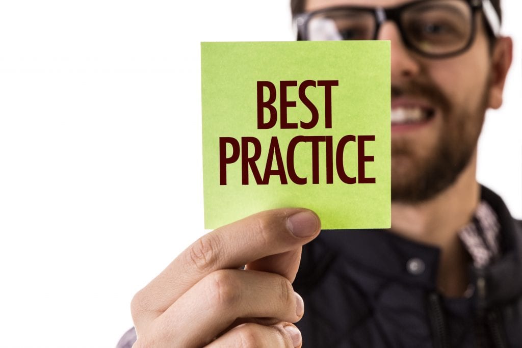 A man holding up a yellow post-it with the word "best practice" on it.