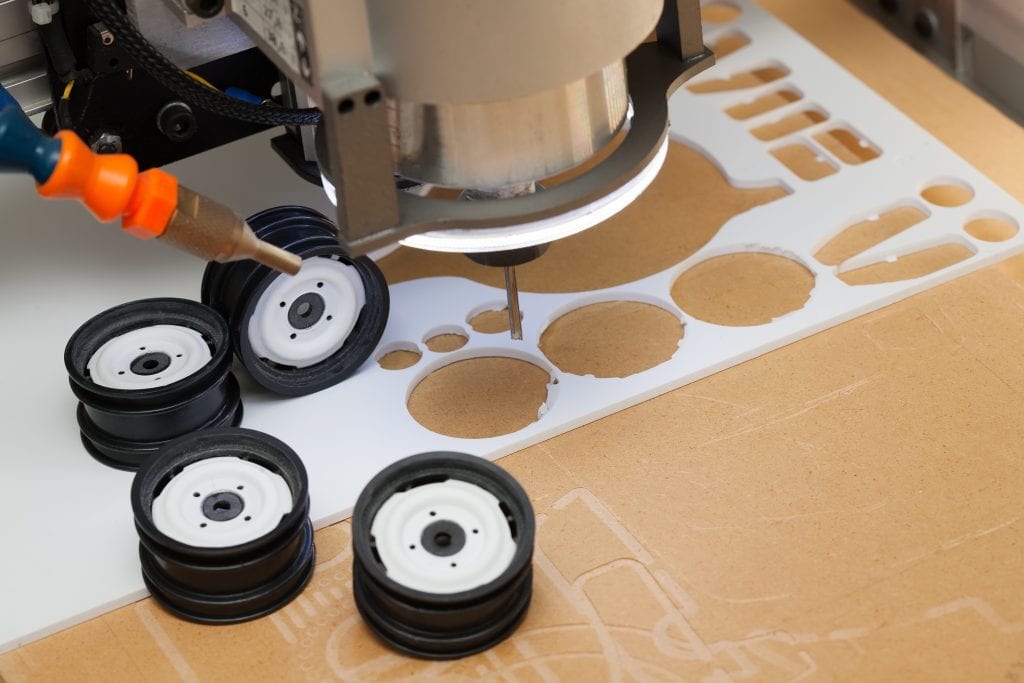 Toy parts designed and precisely cut out by a CNC machine from a sheet of ABS plastic.