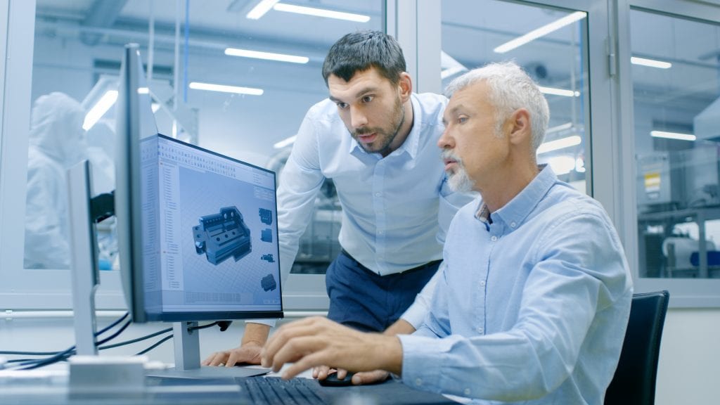 Older gentleman sitting, looking at a 3D model on a computer screen with younger man leaning over to see